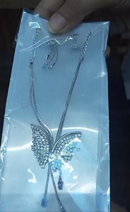 Butterfly-shaped necklace with blue stones on a clear plastic sheet.