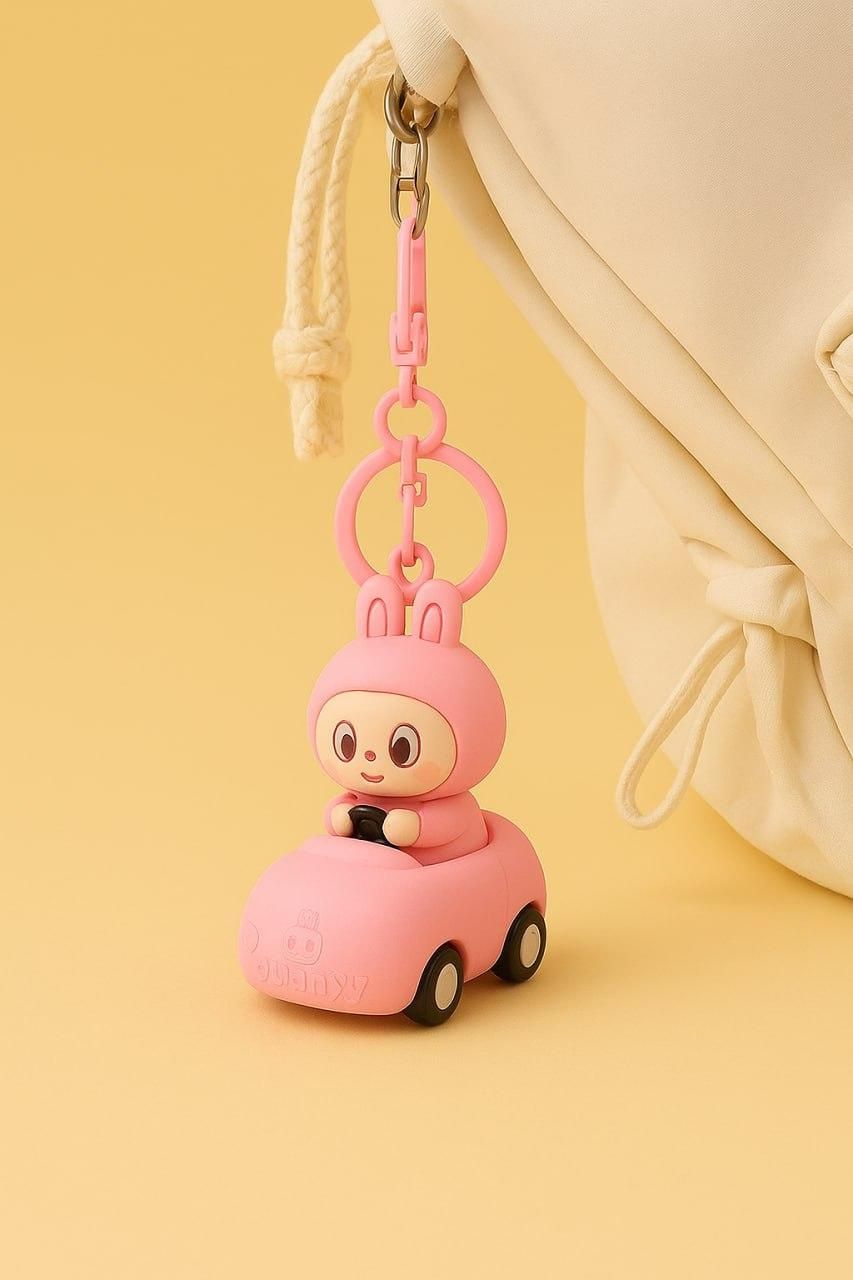 Pink character keychain attached to a beige bag on a yellow background