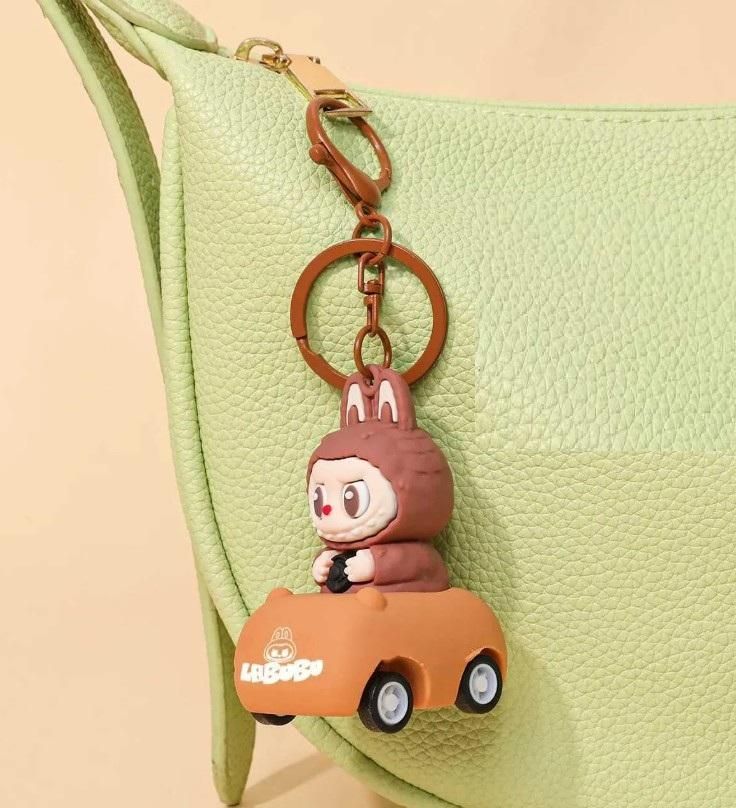 Keychain with cartoon character driving a car attached to a green bag