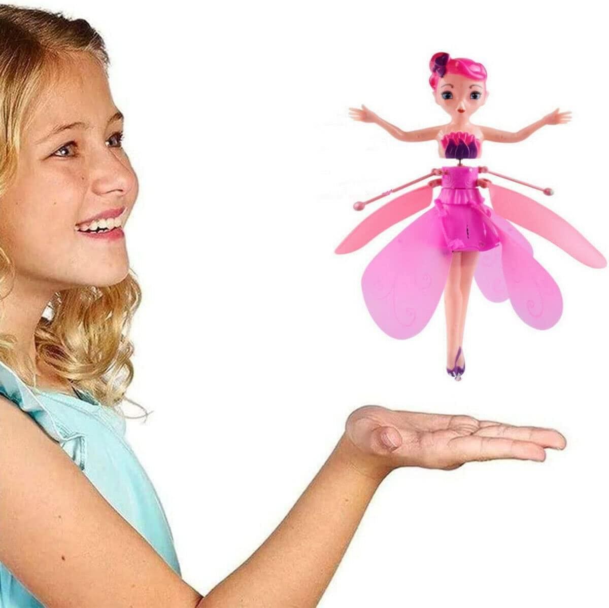 Girl holding a pink fairy toy above her hand with a white background