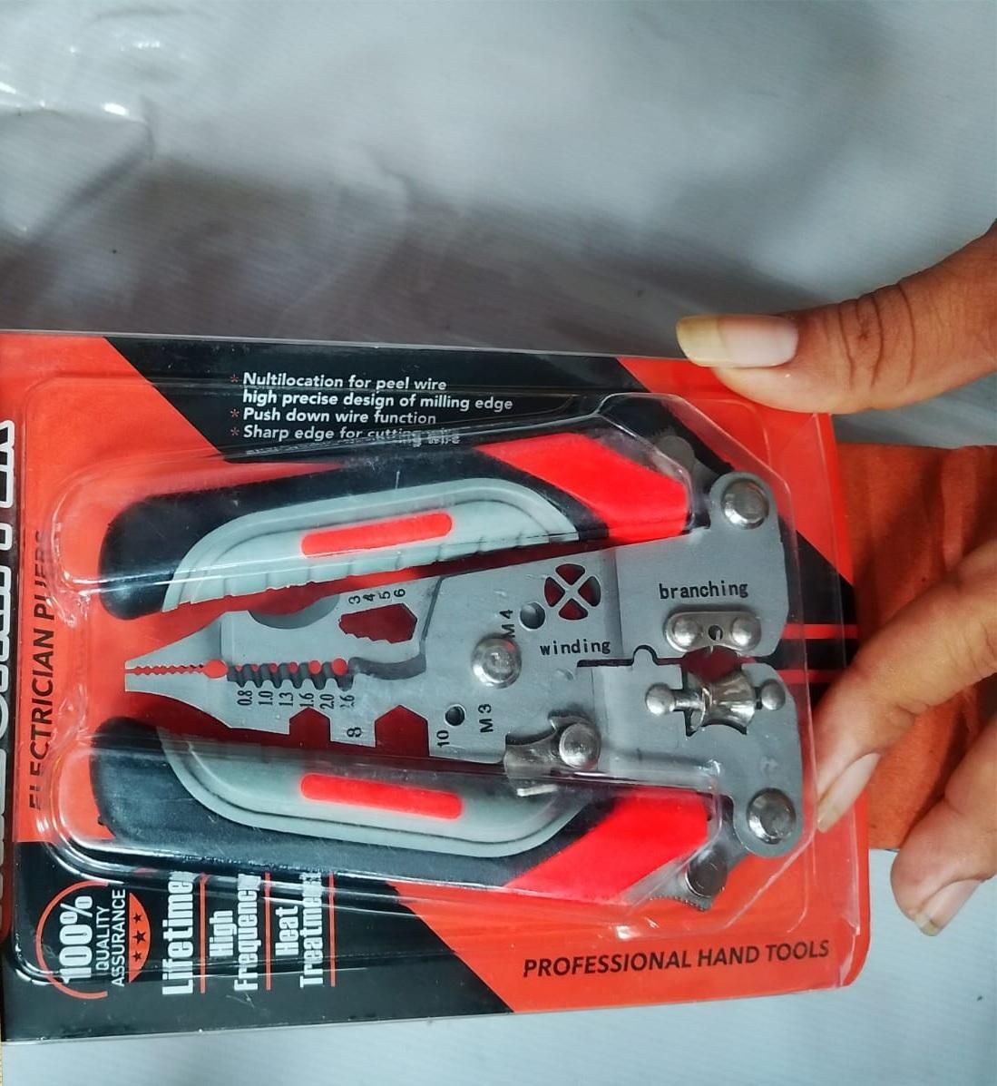 Electrical crimper tool in packaging held by a hand on a gray background