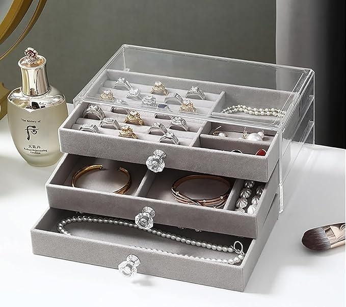 Gray jewelry organizer with rings, bracelets, and necklaces on a white surface.