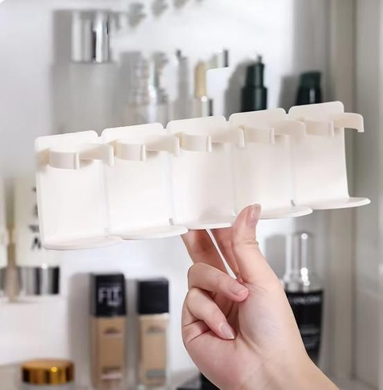 Hand holding a white makeup organizer with a blurred background of cosmetic products.