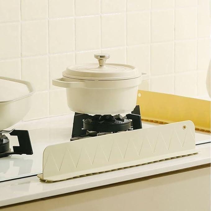 White pot on a stove with a white kitchen towel draped over the edge