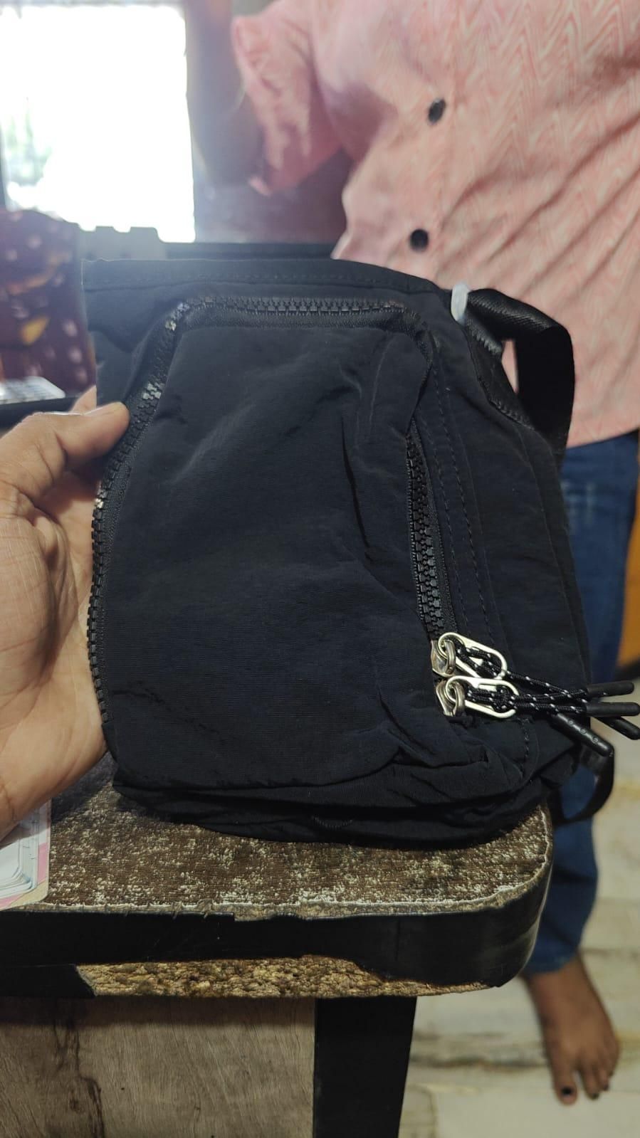 Black face mask held by a hand with a blurred background